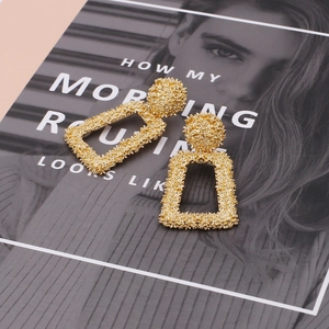 Detailed view of gold geometric trapezoid earrings with textured grainy finish