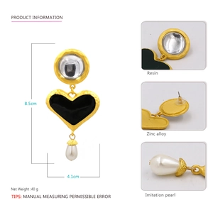 Detail view of retro drop earrings with black resin hearts and teardrop faux pearls