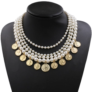 Vintage multi-layer white pearl necklace with embossed gold coin pendants on a black bust