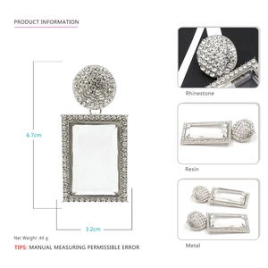 Detailed view of oversized geometric drop earrings featuring crystal studs and resin