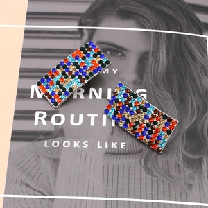 Sparkling geometric curved earrings with multi-colored rhinestones on magazine background