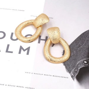 Boucles d'oreilles dorées goutte d'eau avec texture martelée sur fond de magazine