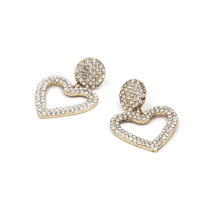 Détail de boucles d'oreilles cœur dorées ornées de micro-cristaux scintillants
