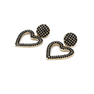 Détail de boucles d'oreilles cœur dorées avec strass noirs et clous pavés