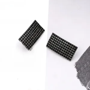 Close-up of gunmetal curved earrings with densely set black rhinestones in a chic layout
