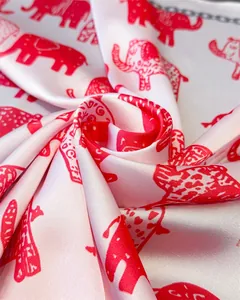 Detailed view of white silk-textured fabric with elegant red elephant print and smooth luster
