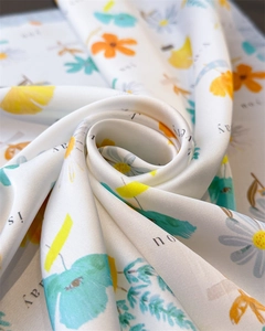 Detailed macro view of pearl white satin scarf with floral prints and text patterns