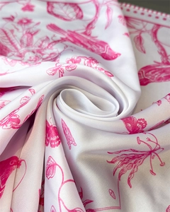 Detail of elegant floral and bird print on white silk-like fabric with vibrant pink flowers