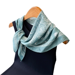 Mint green floral printed square silk scarf styled on a black vest with wooden hanger