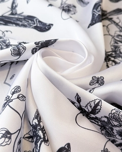Detailed view of elegant bird and floral print on white satin scarf with silky texture