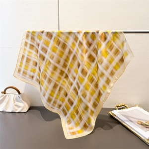 Detail view of silk-like satin square scarf featuring yellow and coffee plaid patterns