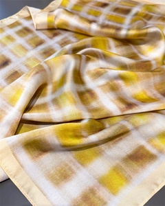 Detailed view of plaid silk scarf featuring elegant yellow and brown checkered patterns