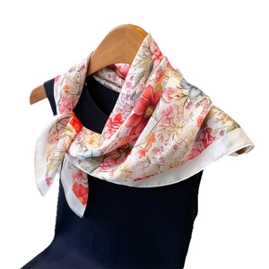 Elegant floral print silk scarf in red and pink draped over a black mannequin