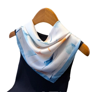 Carré de soie élégant motif floral bleu ciel et aquarelle présenté sur un cintre en bois