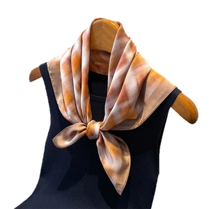 Elegant vintage square silk scarf with warm orange and brown tie-dye pattern on hanger