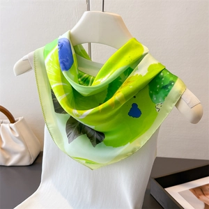 Detailed close-up of fruit green silk scarf featuring abstract patterns and fine stitching