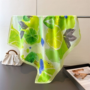Silk scarf featuring refreshing lemon and lime prints on a bright green background