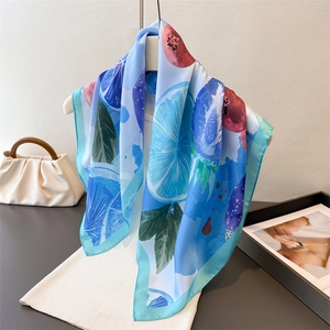 Elegant square silk scarf with vibrant lemon and berry prints on a minimalist white stand