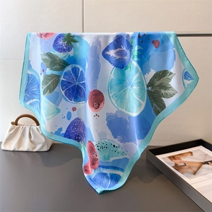 Detail of blue silk scarf featuring lemon and strawberry prints with soft silk luster