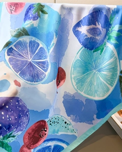 Detail of artistic lemon and fruit print on high-quality silky square neck scarf