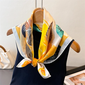 Elegant silk scarf with vibrant lemon print and abstract patterns on a wooden hanger