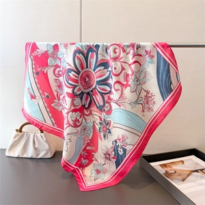 Detail of floral silk scarf with pink and navy patterns draped on a metal stand