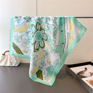Close-up of elegant floral print on mint green satin scarf with silky texture detail