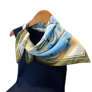 Floral print satin square scarf in blue and yellow colors worn on a black sweater