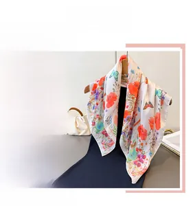 Detail of silk satin scarf featuring orange floral and blue butterfly print patterns
