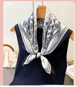 Macro detail of paisley print silk scarf with black and white contrast striped border