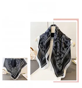 Close-up of elegant black and white paisley pattern scarf with striped border details
