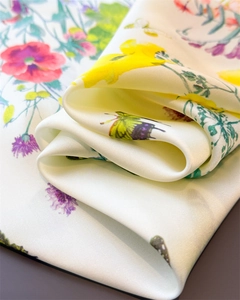 Macro detail of silk scarf featuring colorful butterfly and flower prints on cream fabric