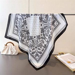 Elegant black and white paisley silk scarf displayed with a luxury white handbag