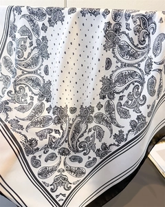 Detailed close-up of premium black and white paisley silk scarf with elegant drape texture