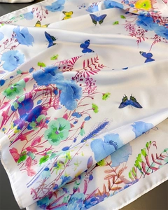 Detailed view of silk-like scarf with blue butterflies and floral prints on white satin