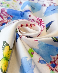 Detail of floral butterfly print silk scarf showing soft fabric texture and vivid blue flowers
