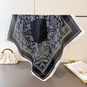 Classic black and white paisley silk-like square scarf draped over a metal hanger