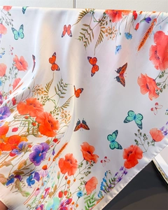 Detail view of butterfly and floral print on smooth silk scarf with soft drape texture