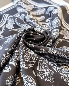 Detail of premium black and white paisley silk scarf with glossy satin texture and swirl