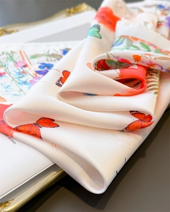 Detailed close-up of white silk scarf featuring vibrant butterfly and floral prints