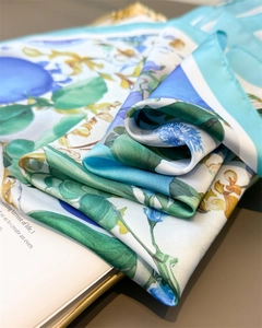 Detail of floral print satin scarf with blue leaf patterns on a magazine backdrop