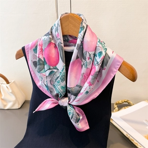 Detailed view of floral silk scarf tied as a bow on wooden hanger with knitwear