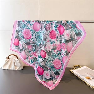 Elegant pink floral silk square scarf with lemon print displayed on a metal rack