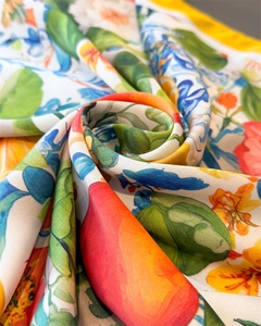 Macro detail of silk scarf showing vibrant floral and citrus prints with satin texture