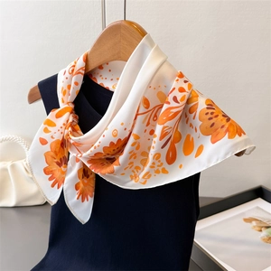 Detailaufnahme des Seidenschals mit Blumenmuster auf einem Kleiderbügel aus hellem Holz