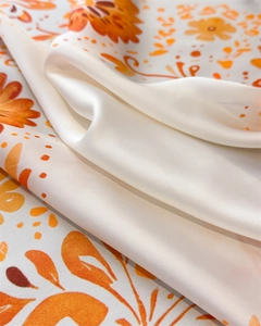 Nahaufnahme des Satin-Halstuchs mit Blumenmuster in Orange und Gelb auf weißer Seide