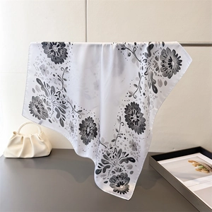 Detail eines eleganten Seidenschals mit schwarzem Blumenmuster und feiner Textur