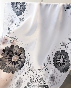 Nahaufnahme eines halbtransparenten Seidenschals mit elegantem schwarz-grauem Blumendruck