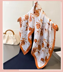 Detail of floral satin scarf with orange flowers on a hanger with a white handbag
