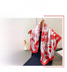 Detail of square satin scarf with vibrant red floral print and rolled edges
